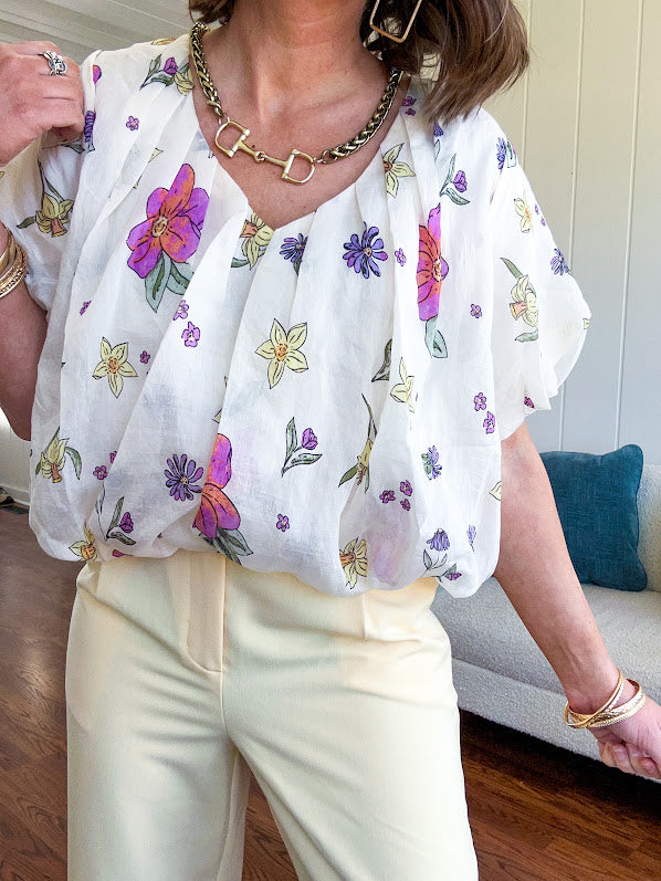 Cream bubble hem blouse with bubble sleeves, pink and yellow florals throughout, V neck and sheer outer layer.