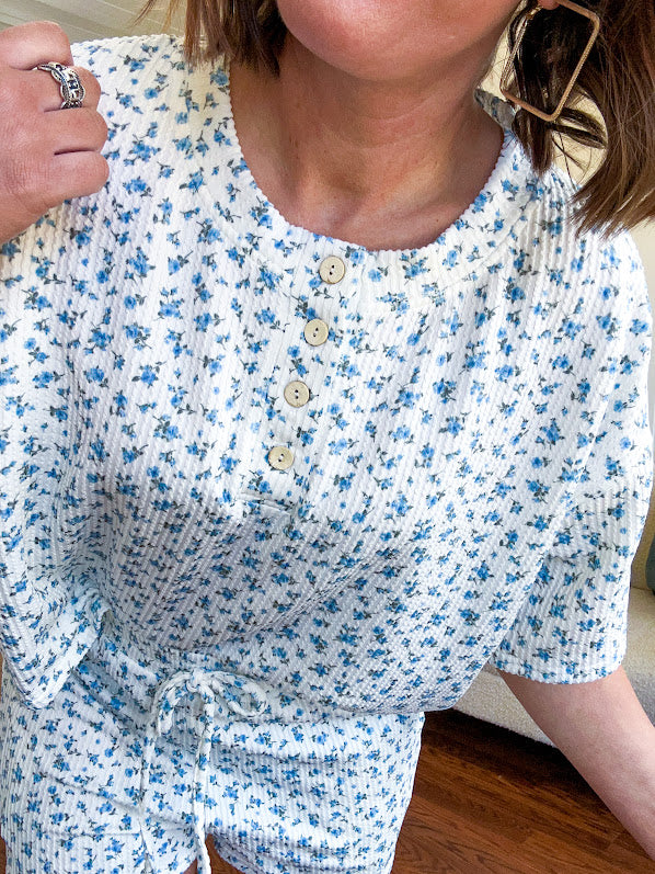 White ribbed Henley style top with small blue florals throughout and matching drawstring, elastic waist shorts with pockets.