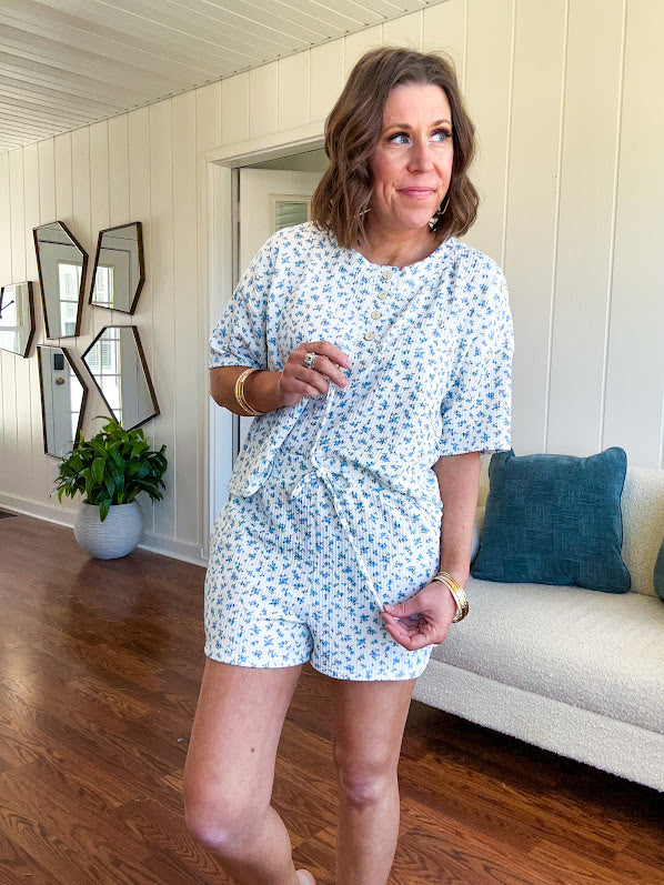 White ribbed Henley style top with small blue florals throughout and matching drawstring, elastic waist shorts with pockets.