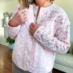 Lightweight quilted pink jacket featuring white and pink florals throughout, zipper front with a covered placket and pockets.