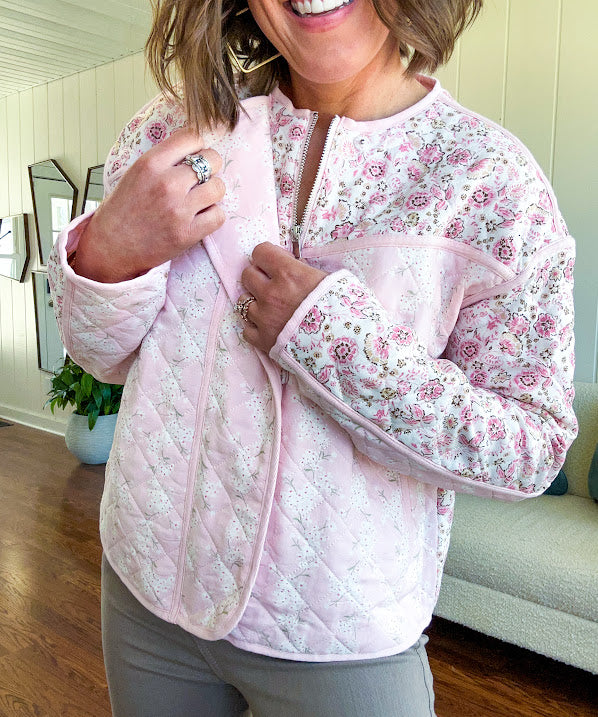 Lightweight quilted pink jacket featuring white and pink florals throughout, zipper front with a covered placket and pockets.