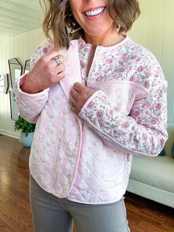 Lightweight quilted pink jacket featuring white and pink florals throughout, zipper front with a covered placket and pockets.