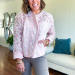 Lightweight quilted pink jacket featuring white and pink florals throughout, zipper front with a covered placket and pockets.