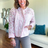 Lightweight quilted pink jacket featuring white and pink florals throughout, zipper front with a covered placket and pockets.