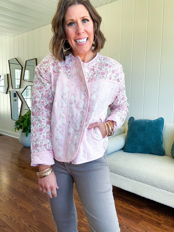 Lightweight quilted pink jacket featuring white and pink florals throughout, zipper front with a covered placket and pockets.