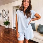 Light blue ribbed cap sleeve 1/4 zip top with matching elastic drawstring waist shorts with scalloped trim at the hem and sleeves, trimmed in white.
