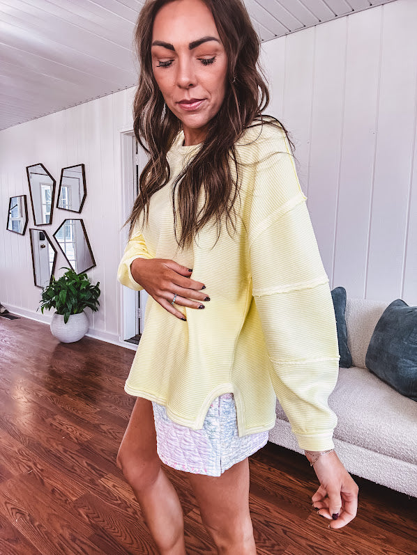 Long sleeved butter yellow ribbed texture pullover with exposed seams throughout and relaxed fit.