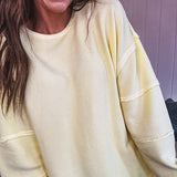 Long sleeved butter yellow ribbed texture pullover with exposed seams throughout and relaxed fit.