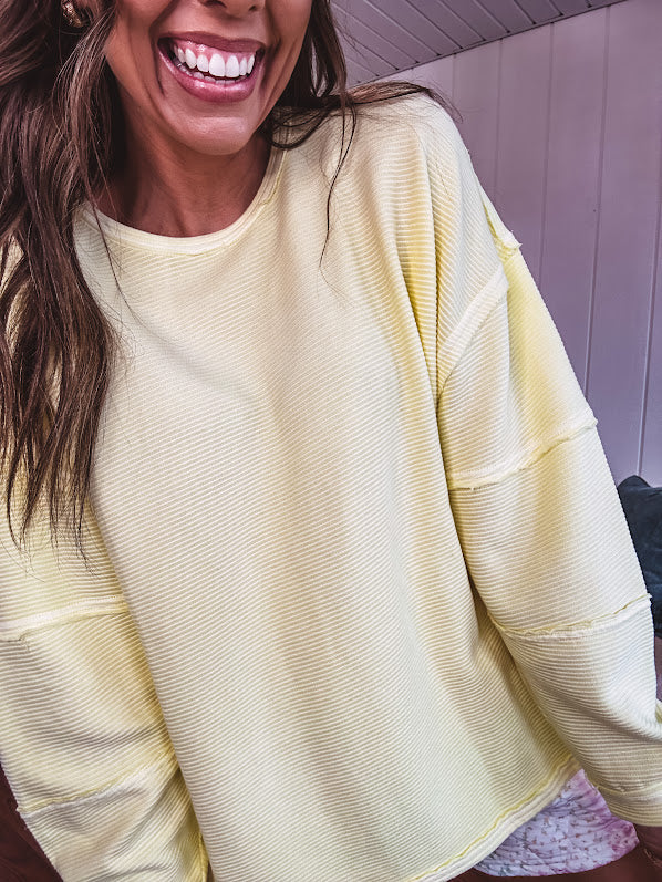 Long sleeved butter yellow ribbed texture pullover with exposed seams throughout and relaxed fit.