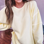Long sleeved butter yellow ribbed texture pullover with exposed seams throughout and relaxed fit.