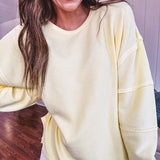 Long sleeved butter yellow ribbed texture pullover with exposed seams throughout and relaxed fit.