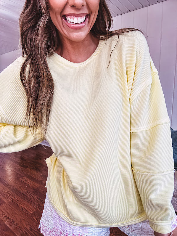 Long sleeved butter yellow ribbed texture pullover with exposed seams throughout and relaxed fit.