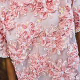 Dusty pink short dress with round neck, short sleeves, tulle overlay with fabric florals with sequined centers and lace accents with pearl trim on the sleeves.