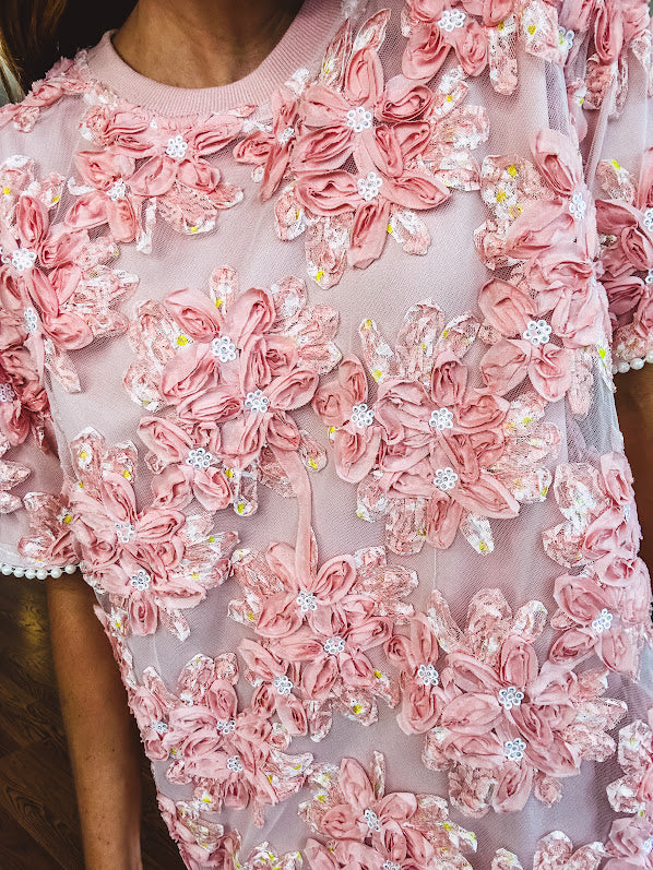 Dusty pink short dress with round neck, short sleeves, tulle overlay with fabric florals with sequined centers and lace accents with pearl trim on the sleeves.