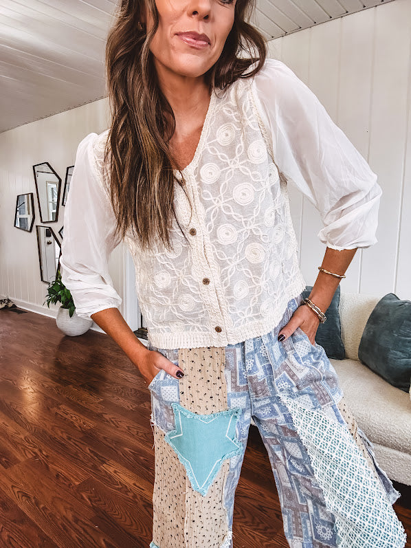Short sheer beige button down long sleeved top with whimsical embroidery throughout and elastic cuffs.