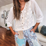 Thin, lightweight wide leg pants with elastic back button and zipper closure, teal, blue and taupe patchwork and mixed fabrics throughout with lace and star patches, pockets and raw hem.