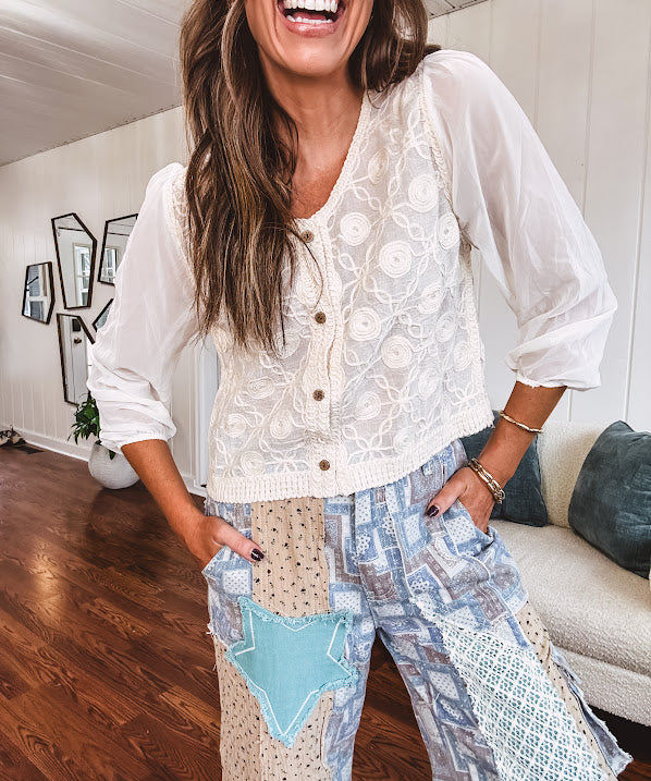 Thin, lightweight wide leg pants with elastic back button and zipper closure, teal, blue and taupe patchwork and mixed fabrics throughout with lace and star patches, pockets and raw hem.