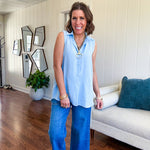 Oversized, flowy button down sleeveless top with collar in light blue.