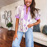 Fully lined lavender and cream blouse with lavender trim at the mock collar and V neck and cuffs, short puffed sleeves and lavender and cream embroidery throughout in an abstract pattern.