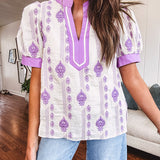 Fully lined lavender and cream blouse with lavender trim at the mock collar and V neck and cuffs, short puffed sleeves and lavender and cream embroidery throughout in an abstract pattern.