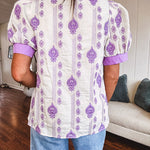Fully lined lavender and cream blouse with lavender trim at the mock collar and V neck and cuffs, short puffed sleeves and lavender and cream embroidery throughout in an abstract pattern.