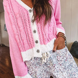 Light pink cable knit cardigan with white trim and flutter hem and cuffs with metal floral buttons down the front.
