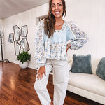 Light blue ribbed texture long sleeved top with sheer blue and green floral inserts at sleeves and ruffled hem with lace embroidery, elastic cuffs and round neck with lace and embroidery trim.