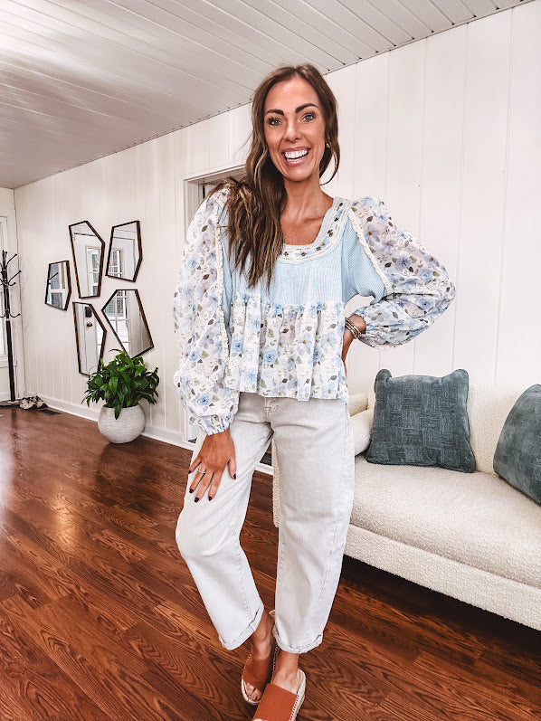 Light blue ribbed texture long sleeved top with sheer blue and green floral inserts at sleeves and ruffled hem with lace embroidery, elastic cuffs and round neck with lace and embroidery trim.