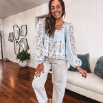 Light blue ribbed texture long sleeved top with sheer blue and green floral inserts at sleeves and ruffled hem with lace embroidery, elastic cuffs and round neck with lace and embroidery trim.