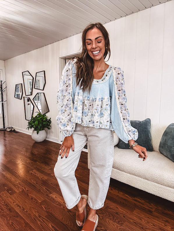 Light blue ribbed texture long sleeved top with sheer blue and green floral inserts at sleeves and ruffled hem with lace embroidery, elastic cuffs and round neck with lace and embroidery trim.