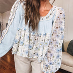Light blue ribbed texture long sleeved top with sheer blue and green floral inserts at sleeves and ruffled hem with lace embroidery, elastic cuffs and round neck with lace and embroidery trim.