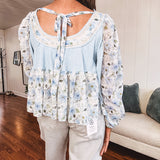 Light blue ribbed texture long sleeved top with sheer blue and green floral inserts at sleeves and ruffled hem with lace embroidery, elastic cuffs and round neck with lace and embroidery trim.