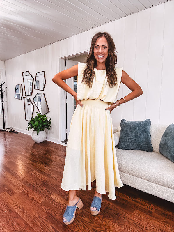 Soft, butter yellow sleeveless top with bubble hem, hook and eye closure at the neck with matching fully lined skirt with flat front waist and pleating with elastic back at the waist, flowy skirt.