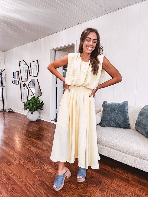 Soft, butter yellow sleeveless top with bubble hem, hook and eye closure at the neck with matching fully lined skirt with flat front waist and pleating with elastic back at the waist, flowy skirt.