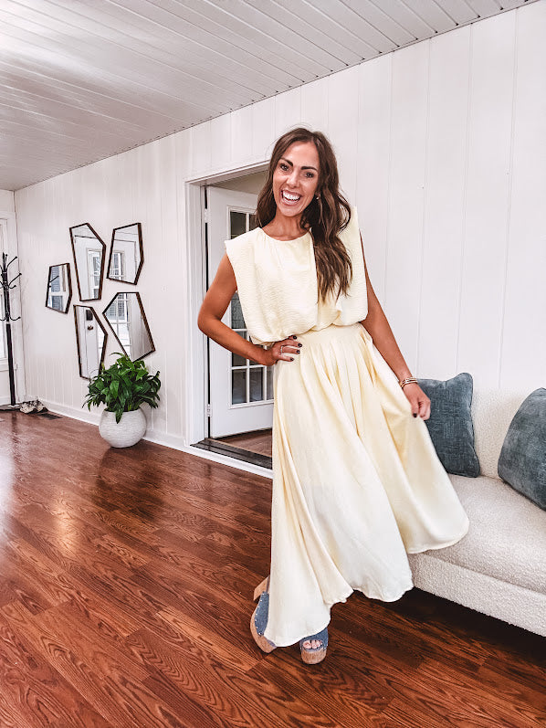 Soft, butter yellow sleeveless top with bubble hem, hook and eye closure at the neck with matching fully lined skirt with flat front waist and pleating with elastic back at the waist, flowy skirt.