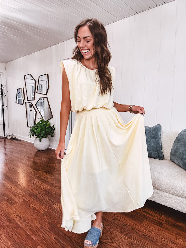Soft, butter yellow sleeveless top with bubble hem, hook and eye closure at the neck with matching fully lined skirt with flat front waist and pleating with elastic back at the waist, flowy skirt.