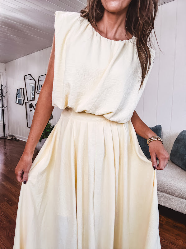 Soft, butter yellow sleeveless top with bubble hem, hook and eye closure at the neck with matching fully lined skirt with flat front waist and pleating with elastic back at the waist, flowy skirt.