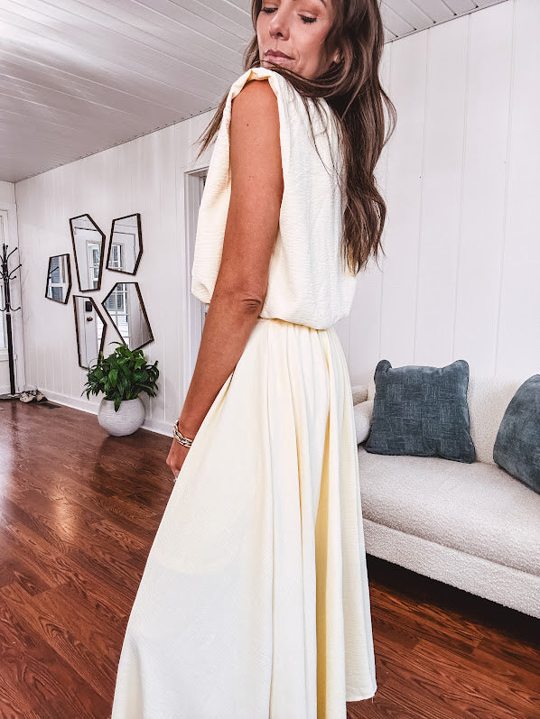 Soft, butter yellow sleeveless top with bubble hem, hook and eye closure at the neck with matching fully lined skirt with flat front waist and pleating with elastic back at the waist, flowy skirt.