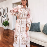 Tan slip dress with long sleeved organza overlay featuring muted florals in pink and cream with vintage inspired design, pearl and gold buttons down the front, cuffs and matching fabric belt with gold accent.