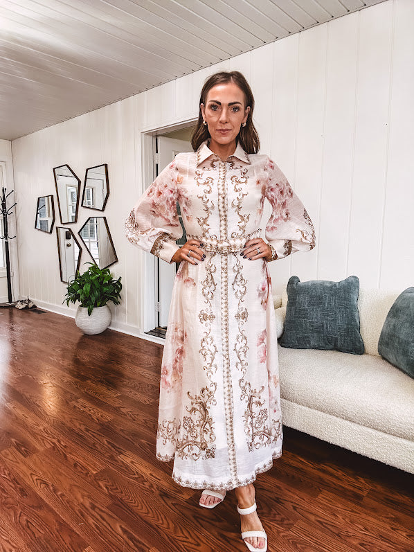 Tan slip dress with long sleeved organza overlay featuring muted florals in pink and cream with vintage inspired design, pearl and gold buttons down the front, cuffs and matching fabric belt with gold accent.