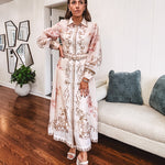 Tan slip dress with long sleeved organza overlay featuring muted florals in pink and cream with vintage inspired design, pearl and gold buttons down the front, cuffs and matching fabric belt with gold accent.