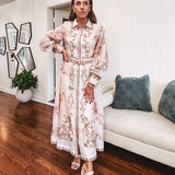 Tan slip dress with long sleeved organza overlay featuring muted florals in pink and cream with vintage inspired design, pearl and gold buttons down the front, cuffs and matching fabric belt with gold accent.