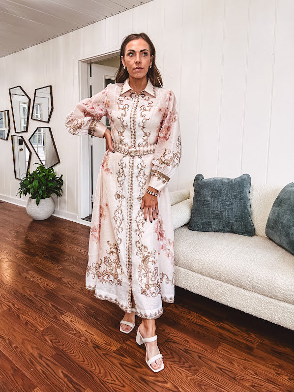 Tan slip dress with long sleeved organza overlay featuring muted florals in pink and cream with vintage inspired design, pearl and gold buttons down the front, cuffs and matching fabric belt with gold accent.
