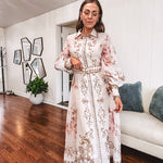 Tan slip dress with long sleeved organza overlay featuring muted florals in pink and cream with vintage inspired design, pearl and gold buttons down the front, cuffs and matching fabric belt with gold accent.