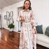 Tan slip dress with long sleeved organza overlay featuring muted florals in pink and cream with vintage inspired design, pearl and gold buttons down the front, cuffs and matching fabric belt with gold accent.