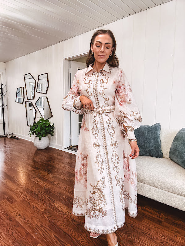 Tan slip dress with long sleeved organza overlay featuring muted florals in pink and cream with vintage inspired design, pearl and gold buttons down the front, cuffs and matching fabric belt with gold accent.