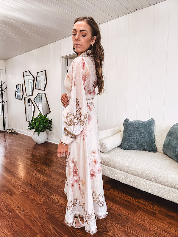Tan slip dress with long sleeved organza overlay featuring muted florals in pink and cream with vintage inspired design, pearl and gold buttons down the front, cuffs and matching fabric belt with gold accent.