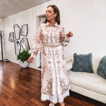 Tan slip dress with long sleeved organza overlay featuring muted florals in pink and cream with vintage inspired design, pearl and gold buttons down the front, cuffs and matching fabric belt with gold accent.