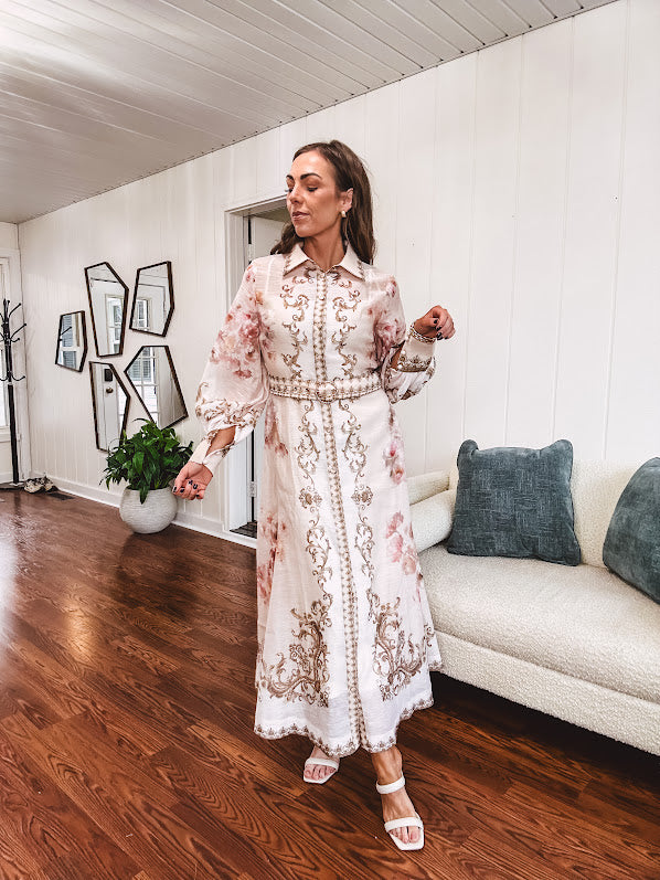 Tan slip dress with long sleeved organza overlay featuring muted florals in pink and cream with vintage inspired design, pearl and gold buttons down the front, cuffs and matching fabric belt with gold accent.