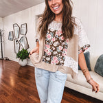 Lightweight ribbed textured taupe top with lace at the yoke and sides and a brown and pink and blue floral patch in the front at at the cuffs of the short sleeves. Oversized.